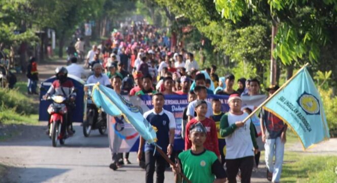 
					MEMBLUDAK : Peserta jalan sehat bersholawat menyusuri ruas jalan dengan gembira. (Foto : Ust. Akiduddin)