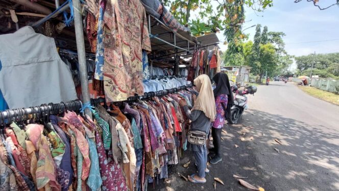 
					Pedagang baju bekas impor di Probolinggo sedang melayani pembeli.