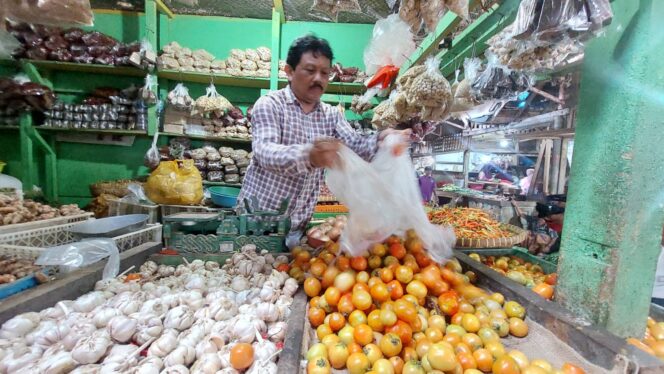 
					Su'eb, pedagang di Pasar Baru sedang menata dagangannya di lapaknya.