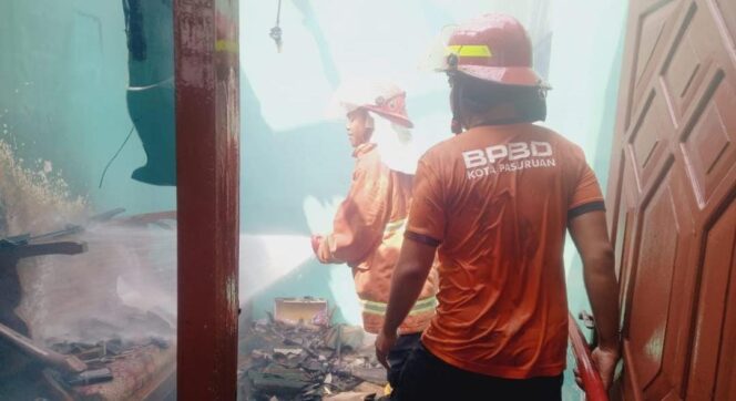 
					PEMADAMAN: Petugas PMK melakukan pemadam api yang membakar rumah di Rejoso. (Moh. Rois)
