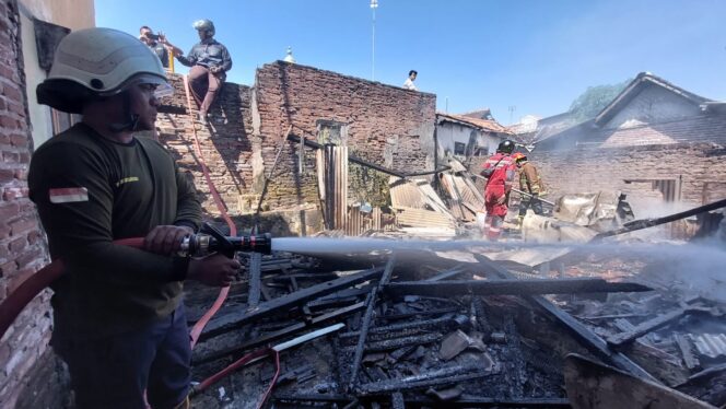 
					Petugas damkar melakukan penyemprotan di dua rumah yang terbakar.