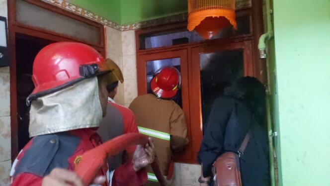 
					Petugas damkar memadamkan rumah yang terbakar.