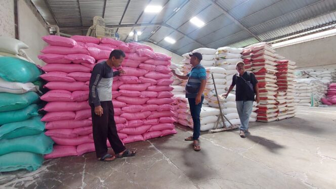 
					Pegawai distributor beras UD. Akas, Kota Probolinggo berdiri di dekat tumpukan beras.