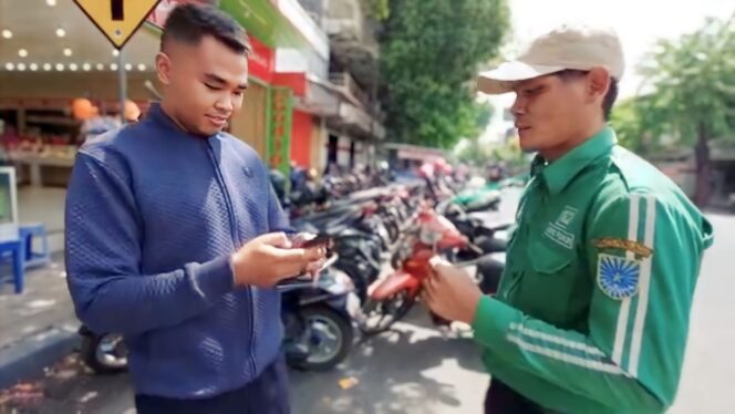 
					NON-TUNAI: Petugas parkir menunjukkan barcode QRIS kepada pelanggan parkir. (Foto: Istimewa)
