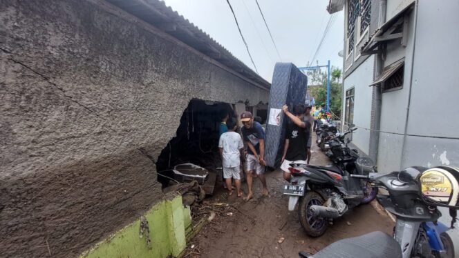 
					BERSIH-BERSIH: Warga terdampak banjir sedang menggotong kasur melewati rumah yang rusak. (foto: Hafiz Rozani).