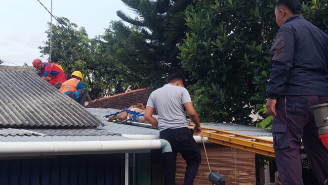
					TEWAS: Petugas gabungan di Kota Probolinggo saat mengevakuasi korban dari atap rumah. (foto: Hafiz Rozani)