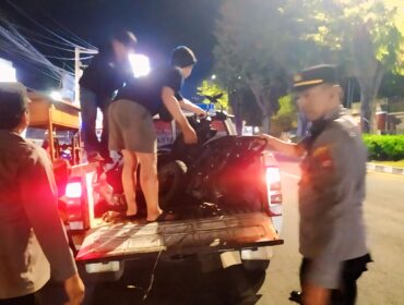 TABRAKAN: Aparat kepolisian saat mengevakuasi motor yang terlibat tabrakan dengan mobil di Kaliwates, Jember. (foto: M. Abd. Rozaq Mubarok).

