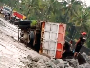 Truk pengangkut pasir dengan Nomor Polisi (Nopol) AG 9965 UG terguling di jalur lahar Semeru.  (Foto: tangkapan layar).

