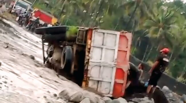 Truk pengangkut pasir dengan Nomor Polisi (Nopol) AG 9965 UG terguling di jalur lahar Semeru.  (Foto: tangkapan layar).

