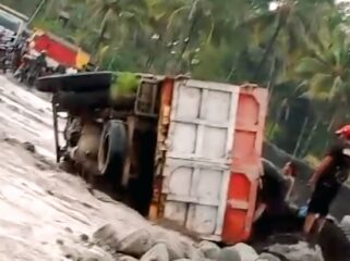 Truk pengangkut pasir dengan Nomor Polisi (Nopol) AG 9965 UG terguling di jalur lahar Semeru.  (Foto: tangkapan layar).
