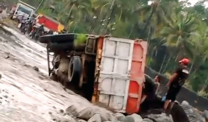 
					Truk pengangkut pasir dengan Nomor Polisi (Nopol) AG 9965 UG terguling di jalur lahar Semeru.  (Foto: tangkapan layar).
