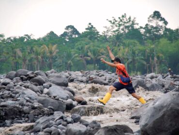 Maman Abdurrahman, warga Jugosari mencoba menyebrangi sungai yang terisolasi akibat banjir lahar gunung semeru membawa material pasir dan bebatuan (Foto: Asmadi).
