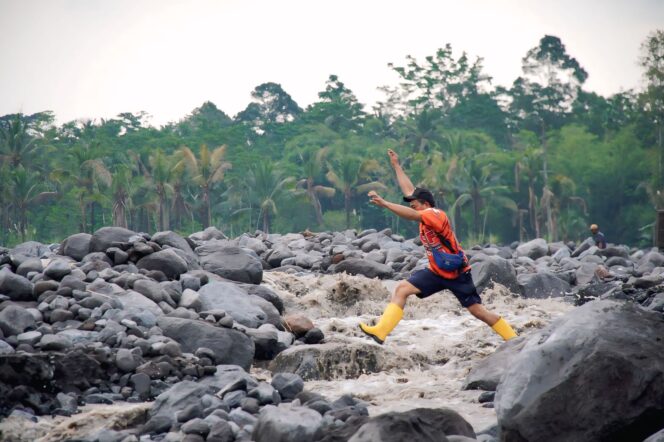 
					Maman Abdurrahman, warga Jugosari mencoba menyebrangi sungai yang terisolasi akibat banjir lahar gunung semeru membawa material pasir dan bebatuan (Foto: Asmadi).
