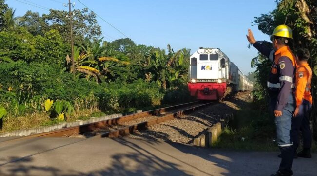 JAGA: Petugas KAI saat menjaga perlintasan sebidang di wilayah Daop 9 Jember selama libur panjang kenaikan Isa Almasih Tahun 2025. (foto: Humas KAI Daop 9 Jember)
