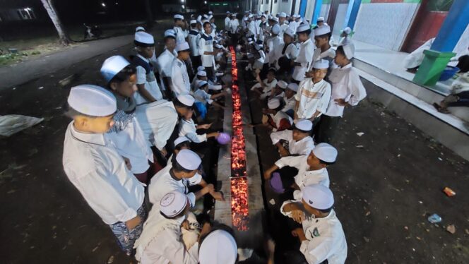 
					TRADISI: Ratusan santri Ponpes Bani Rancang, di Desa Lemahkembar, Kec. Sumberasih, Kab. Probolinggo, saat membakar sate diatas bara api yang memanjang. (foto: Hafiz Rozani).
