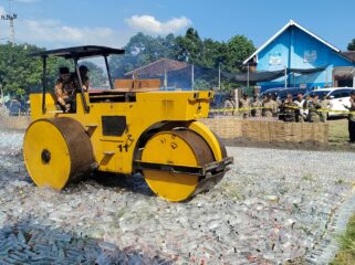 TEGAS: Bupati Probolinggo, Gus Haris, saat menghancurkan puluhan ribu botol miras menggunakan alat berat. (foto: Ali Ya'lu).