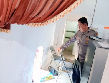 Seorang polisi dari Polsek Grati menunjuk lubang di tembok dapur SDN Kalipang 1, Kecamatan Grati, Kabupaten Pasuruan, yang dibobol pencuri. (Foto: Moh. Rois)