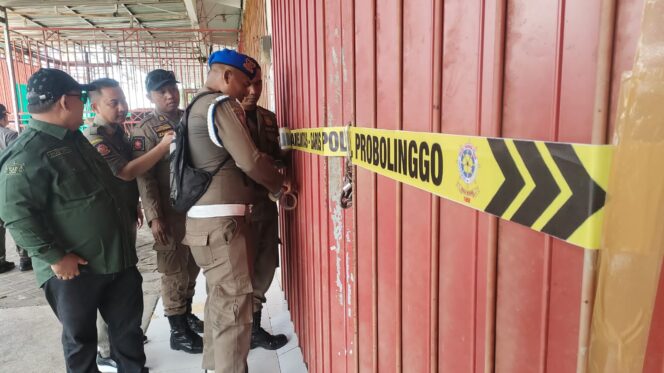 
					SEGEL: Petugas dari Tim Satgas Miras memasang tanda segel di sebuah ruko yang berada di Desa Sumberlele, Kecamatan Kraksaan, Kabupaten Probolinggo. (foto: Ali Ya'lu).