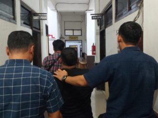 DITAHAN: Terduga pelaku penipuan, Sigit (memakai baju hitam dan diapit 2 petugas kepolisian) saat digelandang anggota Polres Probolinggo Kota. (foto: Hafiz Rozani).
