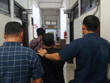 DITAHAN: Terduga pelaku penipuan, Sigit (memakai baju hitam dan diapit 2 petugas kepolisian) saat digelandang anggota Polres Probolinggo Kota. (foto: Hafiz Rozani).

