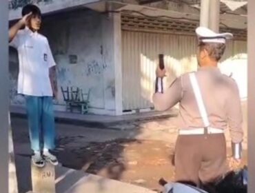 Seorang pelajar menyanyikan lagu Indonesia Raya di pinggir jalan usai terjaring Operasi Patuh Semeru 2025 di Pasuruan.