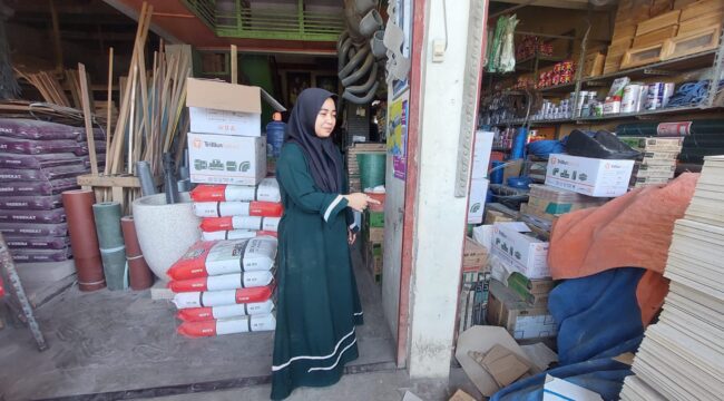 KEMALINGAN: Istri korban  Abdurrahman, menunjukkan pintu toko bangunan di Kota Probolinggo, yang kurang rapat saat pelaku masuk. (foto: Hafiz Rozani).
