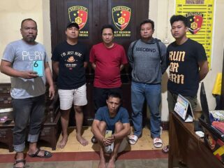 DITANGKAP: Nurahmad (duduk dengan memegang ponsel curiannya) usai diamankan oleh anggota Polsek Dringu, Polres Probolinggo. (foto: istimewa)
