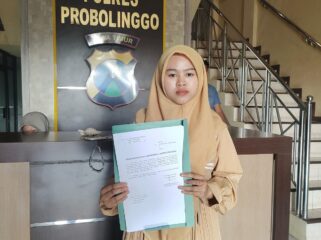 LAPORAN: Dita Dwi Angela Putri menunjukkan surat laporannya di Polres Probolinggo, Rabu (30/7/25) siang. (foto: Ali Ya'lu).