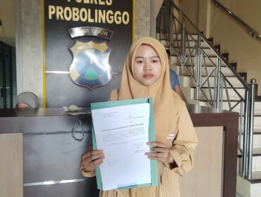 LAPORAN: Dita Dwi Angela Putri menunjukkan surat laporannya di Polres Probolinggo, Rabu (30/7/25) siang. (foto: Ali Ya'lu).