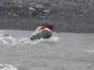 Seorang ayah yang menggendong anaknya terjatuh saat menyeberangi Sungai Regoyo. (Foto: tangkapan layar).
