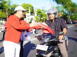BERBAGI: Wali Kota Probolinggo, dr. Aminuddin, membagikan bendera merah putih kepada para pengguna jalan. (foto: istimewa)