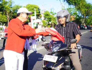 BERBAGI: Wali Kota Probolinggo, dr. Aminuddin, membagikan bendera merah putih kepada para pengguna jalan. (foto: istimewa)