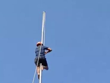 Petugas dari BPBD memanjat tiang dan memperbaiki tali bendera yang putus. (Foto : tangkapan layar).
