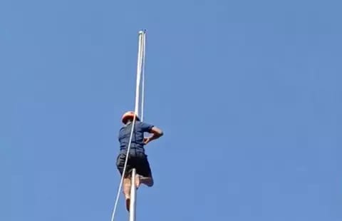 Petugas dari BPBD memanjat tiang dan memperbaiki tali bendera yang putus. (Foto : tangkapan layar).
