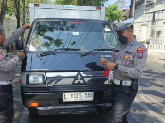 BAGI BENDERA: Anggota Satlantas Polres Probolinggo Kota saat membagikan bendera merah putih ke pengguna kendaraan. (foto: istimewa)