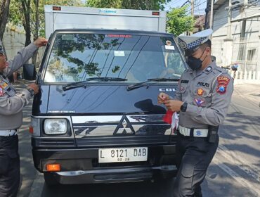 BAGI BENDERA: Anggota Satlantas Polres Probolinggo Kota saat membagikan bendera merah putih ke pengguna kendaraan. (foto: istimewa)