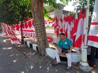 MUSIMAN: Penjual bendera di Jalan Panglima Sudirman, Kota Probolinggo, Mansyur, tengah menunggu pembeli. (foto: Hafiz Rozani).