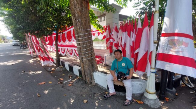MUSIMAN: Penjual bendera di Jalan Panglima Sudirman, Kota Probolinggo, Mansyur, tengah menunggu pembeli. (foto: Hafiz Rozani).