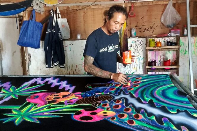 
					Rachmad dengan karyanya, batik fosfor. (Foto: Istimewa.)