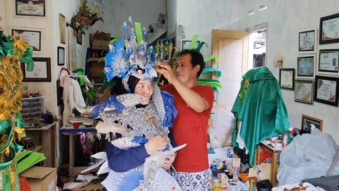 
					Mahdi, perajin sekaligus penyedia jasa persewaan kostum karnaval di Pasuruan, tengah menyiapkan busana.
