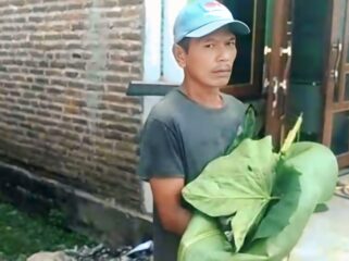 TAK TERTOLONG: Warga menggendong jasad bayi laki-laki yang di temukan hanyut di Sungai Bedadung Jember, dibungkus daun talas. (Foto: Istimewa).
