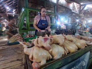 MAHAL: Penjual daging ayam potong di Pasar Baru Kota Probolinggo, Murdiana sedang memotong daging ayam jualannya. (foto: Hafiz Rozani).
