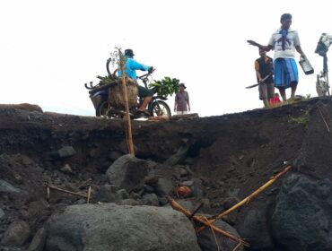 Warga bergotong royong memperbaiki jalan yang rusak di sekitar aliran Sungai Regoyo. (Foto: Asmadi).
