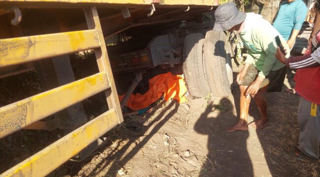 TERLINDAS: Korban (tertutup kain warna oranye) berada dibawah kolong truk di Jalan Raya Tongas Probolinggo. (foto: Hafiz Rozani).