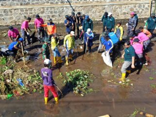 TURUN: Khofifah Indar Pawaransa, Gubernur Jawa Timur (berkerudung biru) saat terjun ke sungai Legundi Probolinggo untuk membersihkan sampah. (foto: Hafiz Rozani).
