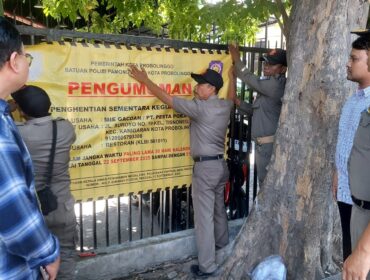 DITUTUP: Anggota Satpol PP Kota Probolinggo Saat memasang banner penutupan Mie Gacoan, Senin (22/9/25) siang. (foto: Hafiz Rozani).
