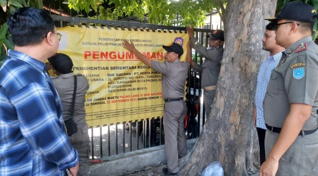 DITUTUP: Anggota Satpol PP Kota Probolinggo Saat memasang banner penutupan Mie Gacoan, Senin (22/9/25) siang. (foto: Hafiz Rozani).
