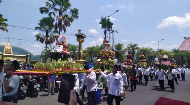 MERIAH: Warga membawa gunungan hasil bumi untuk disedekahkan kepada masyarakat setelah didoakan bersama, di Alun-alun Kota Jember. (Foto: M. Abd Rozaq Mubarok).