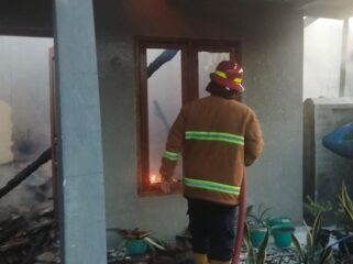 SEMPROT: Petugas Damkar Kabupaten Probolinggo sedang memadamkan api di rumah Suari di Desa Talkadang, Kecamatan Kotaanyar. (foto: Ali Ya'lu).