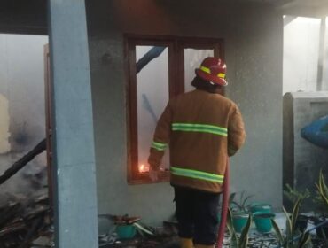 SEMPROT: Petugas Damkar Kabupaten Probolinggo sedang memadamkan api di rumah Suari di Desa Talkadang, Kecamatan Kotaanyar. (foto: Ali Ya'lu).